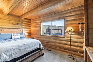 Carpeted bedroom featuring rustic walls, wooden ceiling, and beam ceiling