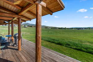 Wooden terrace featuring a rural view, a grill, and a lawn