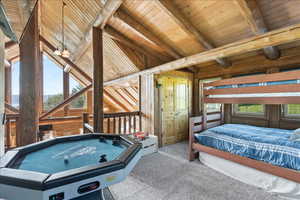 Bedroom featuring vaulted ceiling with beams, light colored carpet, wood walls, and wooden ceiling