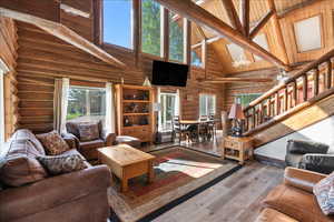 Living room featuring hardwood / wood-style floors, high vaulted ceiling, and beamed ceiling