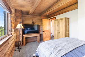 Bedroom with wooden ceiling, rustic walls, beamed ceiling, and carpet flooring