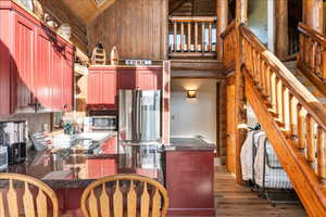 Kitchen with stainless steel appliances, dark hardwood / wood-style floors, high vaulted ceiling, and kitchen peninsula