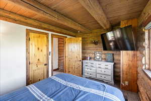 Carpeted bedroom featuring wood ceiling and beamed ceiling