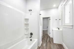 Bathroom featuring wood-type flooring, shower / bathing tub combination, and vanity