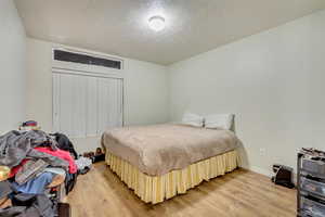 Bedroom with a textured ceiling and light wood-type flooring