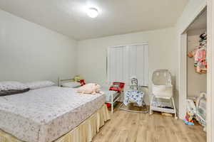 Bedroom with a textured ceiling and light hardwood / wood-style floors