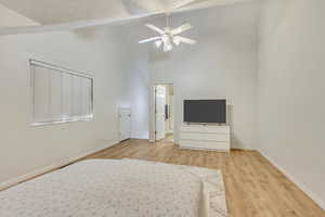 Unfurnished bedroom featuring ceiling fan, high vaulted ceiling, a textured ceiling, and light hardwood / wood-style floors