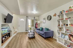 Living room with a healthy amount of sunlight, a textured ceiling, and light wood-type flooring