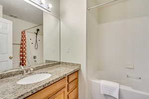 Bathroom featuring vanity and shower / bathtub combination with curtain