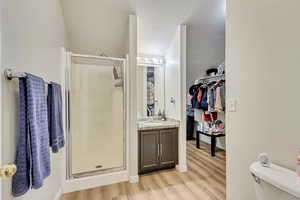 Bathroom featuring hardwood / wood-style floors, vanity, toilet, a shower with door, and a textured ceiling