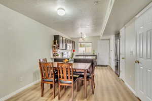 Dining area with light hardwood / wood-style floors and a textured ceiling