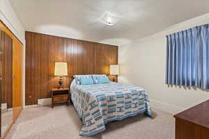 Bedroom with carpet floors, a closet, and wood walls