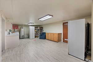 Basement with light hardwood / wood-style floors and gas water heater