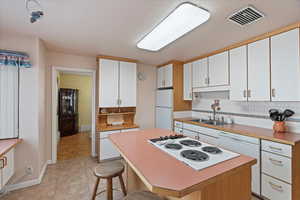 Kitchen with white cabinetry, sink, white appliances, and a center island