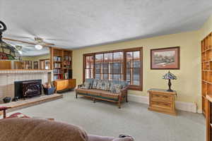 Living room featuring carpet, a wood stove, and a textured ceiling