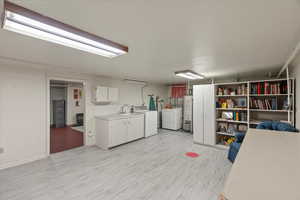 Interior space with water heater, washer and dryer, and light hardwood / wood-style floors