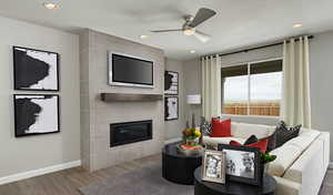 Living room featuring a tiled fireplace, ceiling fan, hardwood / wood-style flooring, and a textured ceiling