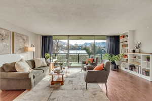 Living room featuring wood-type flooring, floor to ceiling windows, and a textured ceiling