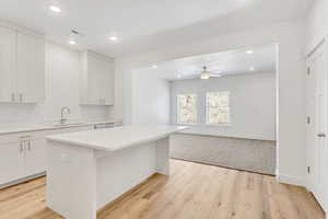 Kitchen featuring light hardwood / wood-style flooring, sink, a kitchen island, and white cabinets