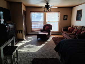 Living room featuring crown molding, ceiling fan, baseboard heating, and light carpet