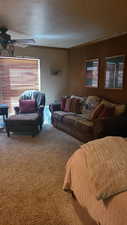 Living room with ceiling fan, carpet floors, a textured ceiling, and wood walls