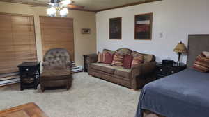 Carpeted bedroom with crown molding, ceiling fan, and a baseboard heating unit