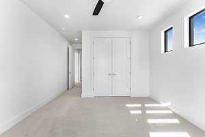 Unfurnished bedroom featuring light carpet, ceiling fan, and a closet