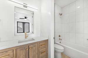 Full bathroom with ceiling fan, tiled shower / bath, vanity, and toilet