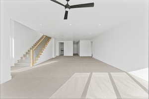 Unfurnished living room featuring light colored carpet and ceiling fan