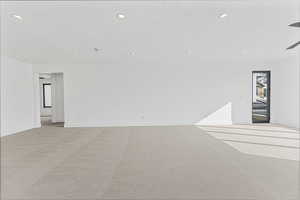 Empty room with light colored carpet and a textured ceiling