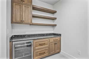 Bar featuring beverage cooler and dark stone counters