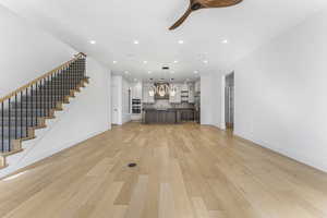 Unfurnished living room featuring ceiling fan and light hardwood / wood-style flooring