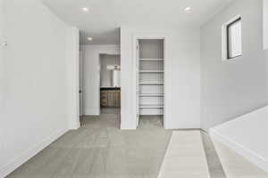 Interior space with a spacious closet, light colored carpet, ensuite bath, and a closet