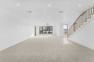 Unfurnished living room featuring ceiling fan, light colored carpet, and a textured ceiling