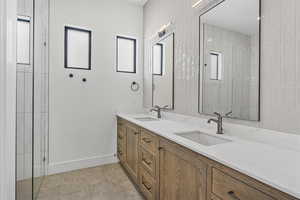 Bathroom featuring vanity, tile patterned flooring, and tiled shower