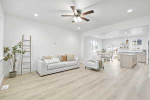 Living room with ceiling fan and light hardwood / wood-style flooring