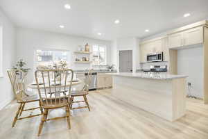 Kitchen featuring sink, light stone counters, light hardwood / wood-style flooring, a kitchen island, and stainless steel appliances