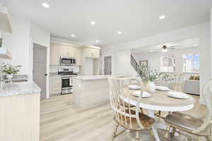 Dining room with sink, ceiling fan, and light wood-type flooring