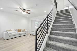 Staircase with hardwood / wood-style floors and ceiling fan