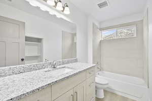 Full bathroom featuring hardwood / wood-style flooring, tiled shower / bath, vanity, and toilet