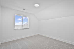 Bonus room with lofted ceiling and carpet flooring