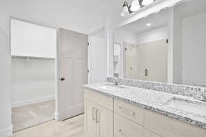 Bathroom featuring walk in shower, vanity, and hardwood / wood-style flooring