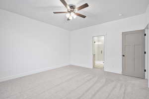 Unfurnished bedroom with ceiling fan, light colored carpet, and ensuite bathroom