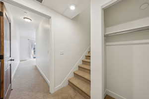 Hallway featuring light colored carpet