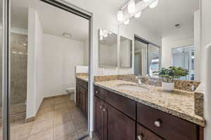 Bathroom with vanity, a shower with shower door, tile patterned floors, and toilet