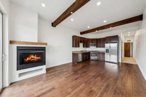 Kitchen featuring hardwood / wood-style flooring, dark brown cabinets, stainless steel appliances, and beamed ceiling