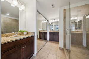 Bathroom with a shower with door, vanity, and tile patterned flooring