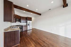 Kitchen featuring sink, appliances with stainless steel finishes, dark hardwood / wood-style floors, beamed ceiling, and light stone countertops