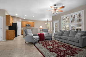 Living room featuring ceiling fan with notable chandelier and light tile patterned floors