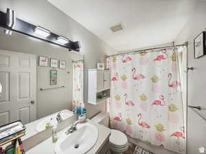 Full bathroom featuring shower / tub combo, vanity, a textured ceiling, and toilet